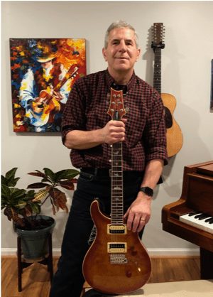 A person holding a guitar
Description automatically generated