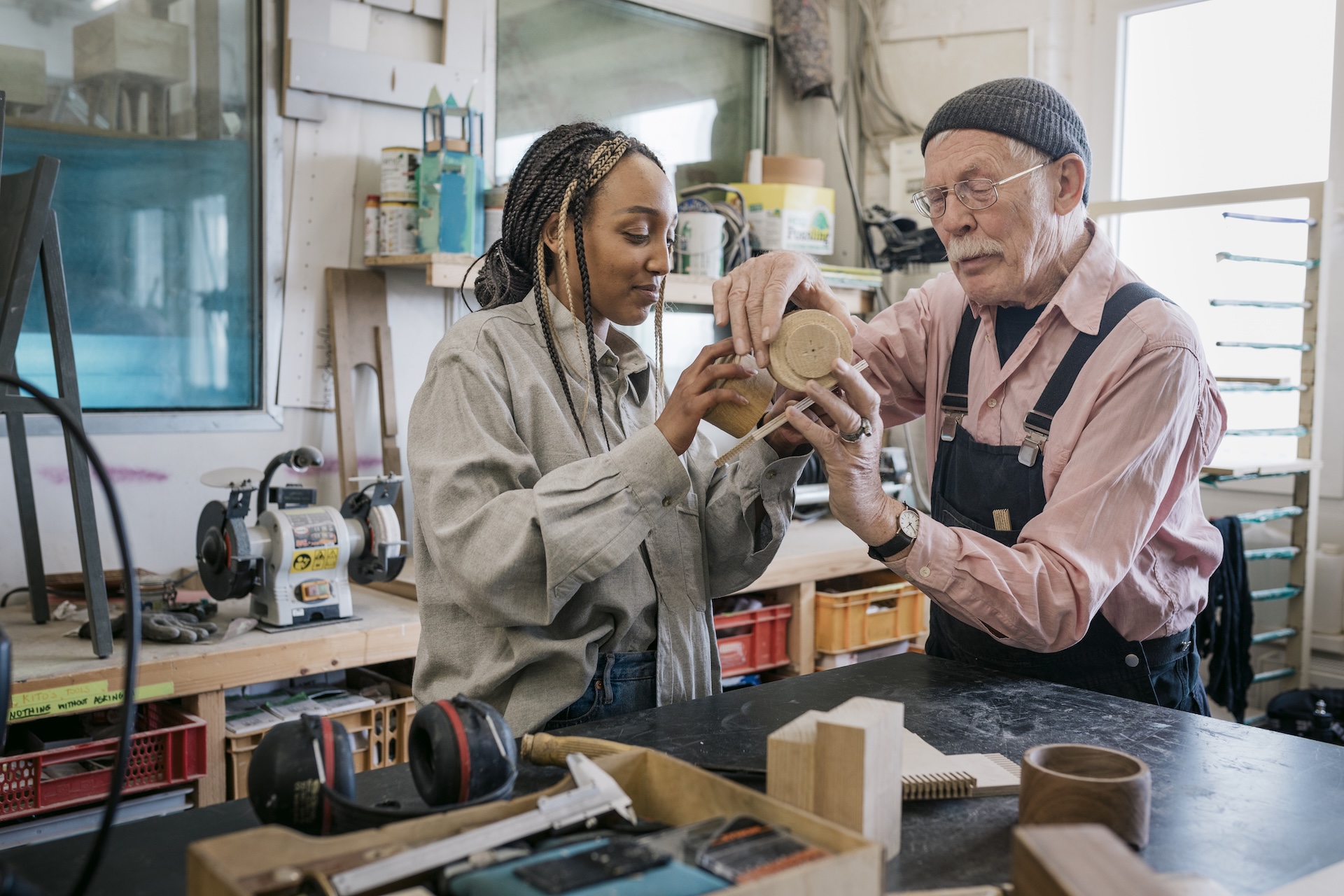 A mature wood workshop owner assisting a student with a project